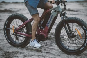 a man riding an electric bike on the beach